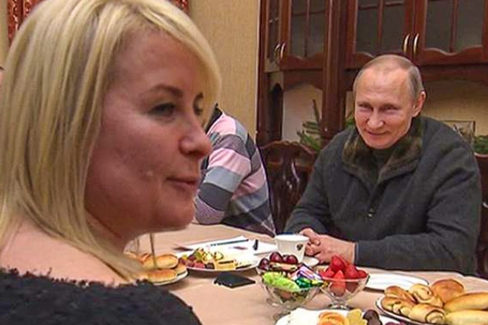 Eine blonde Frau sitzt gegenüber Putin