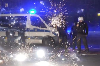 Polizeibeamte stehen hinter explodierendem Feuerwerk: In Hamburg will man die Silvesterkrawalle schnell aufarbeiten.