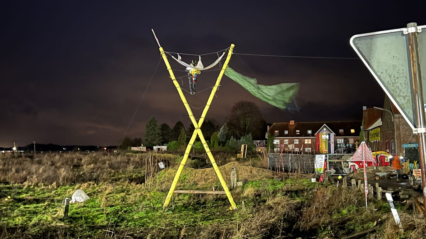 Das gelbe X am Ortseingang von Lützerath ist ein Symbol für den Widerstand gegen die Räumung. Eine Aktivistin hat sich mit Seilen daran festgebunden.