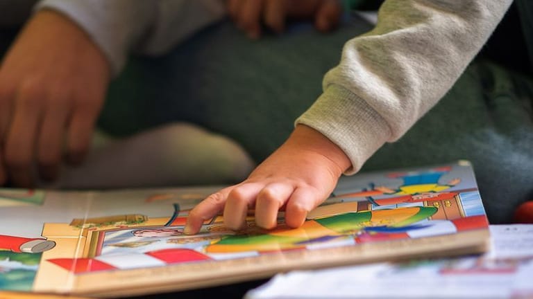 Eine Kinderhand zeigt auf ein Buch (Symbolfoto): Die Bibliothek kam zeitweilig in den Räumen eines Vereins unter.