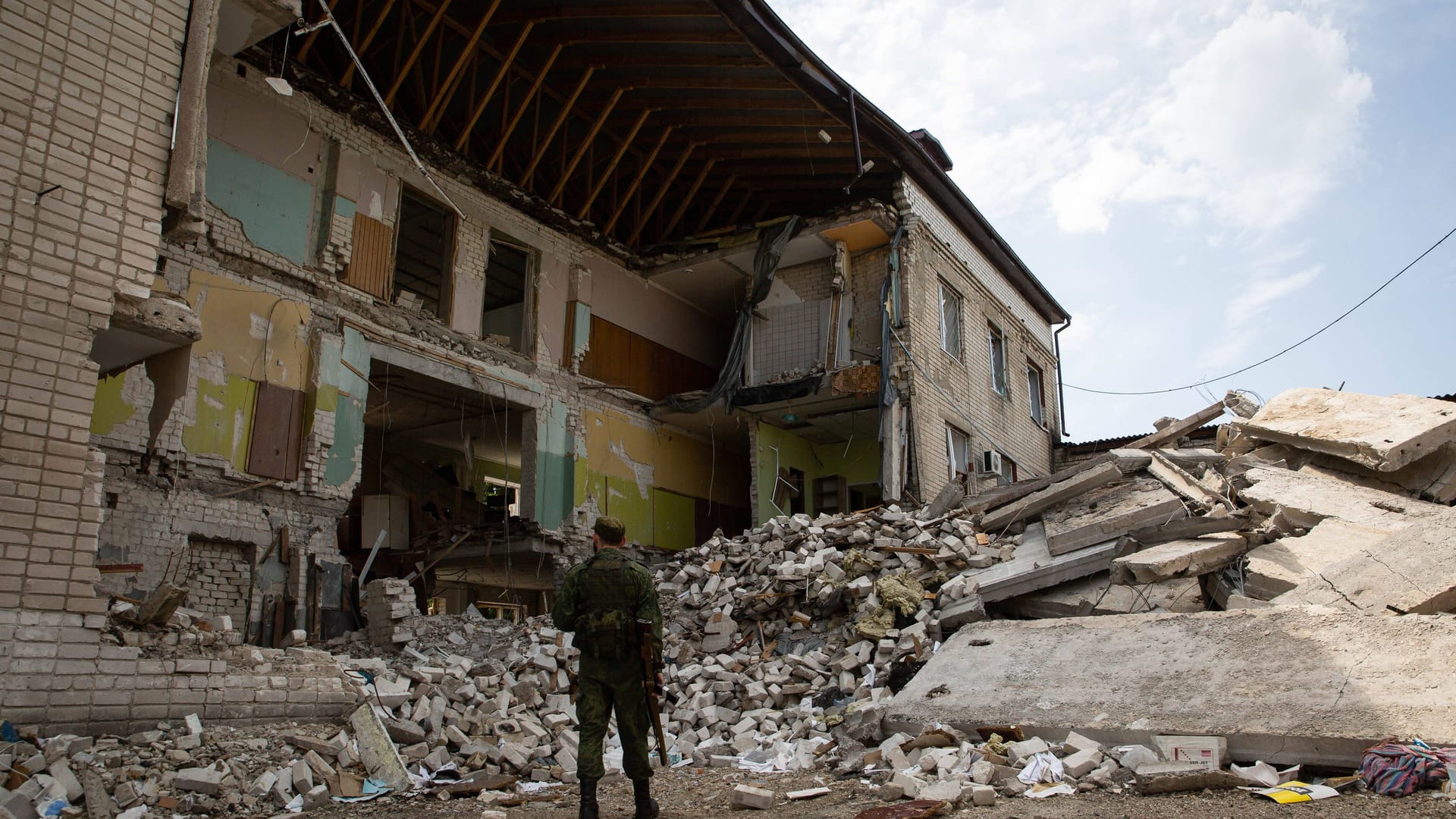 Zerstörte Kreminna: Ein Angehöriger der Volksmiliz der LPR steht vor den durch Granatenbeschuss beschädigten Büros des Innenministeriums in der ukrainischen Stadt Kreminna.