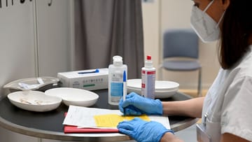 Eine Ärztin füllt eine Impfbescheinigung aus (Symbolbild): Ab Februar müssen die Beschäftigten in Arztpraxen in Baden-Württemberg keine Masken mehr tragen.