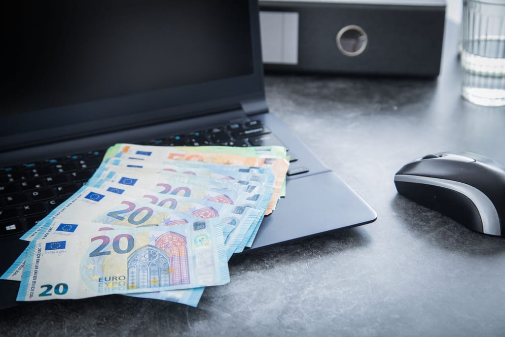 Euroscheine liegen auf einem Laptop (Symbolbild): Kapitalerträge erwirtschaftet? 2023 bleibt davon mehr übrig. Dank des gestiegenen Sparerpauschbetrags.