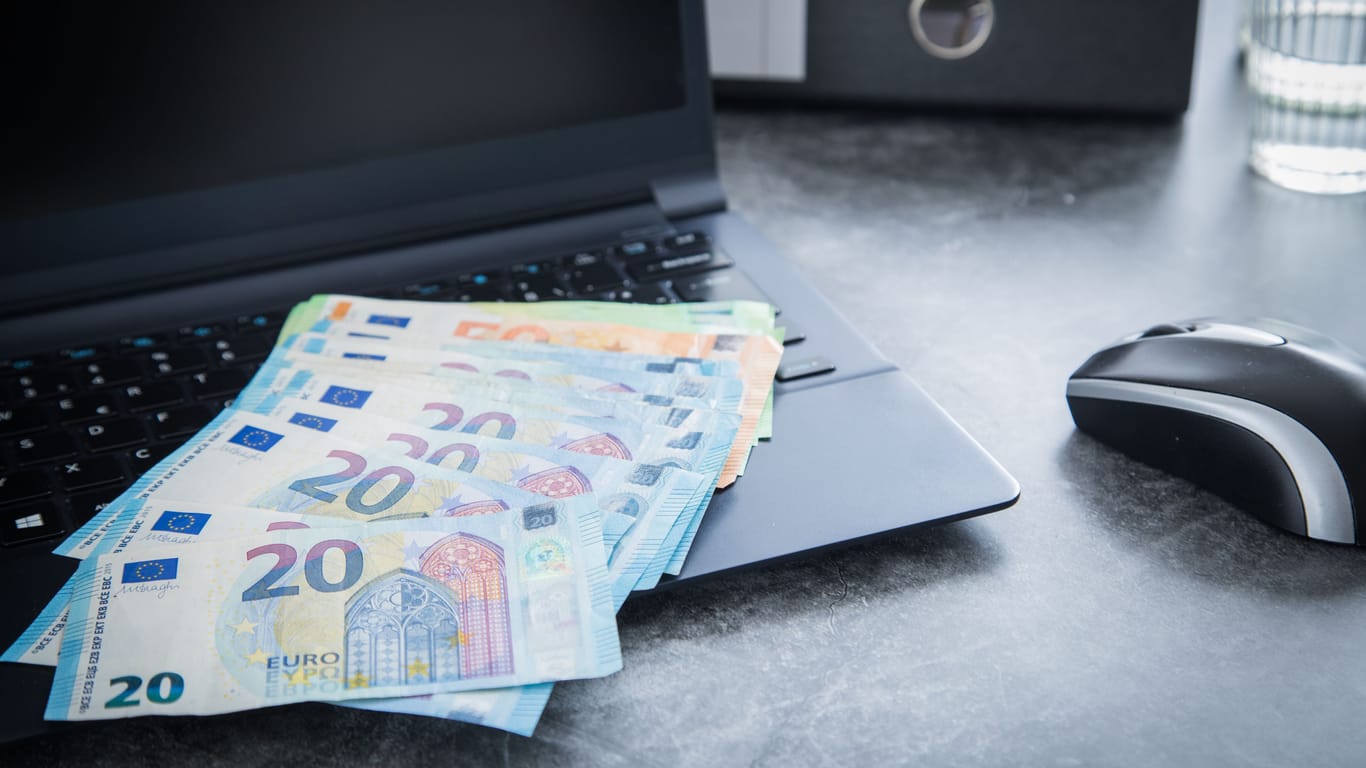 Euroscheine liegen auf einem Laptop (Symbolbild): Kapitalerträge erwirtschaftet? 2023 bleibt davon mehr übrig. Dank des gestiegenen Sparerpauschbetrags.