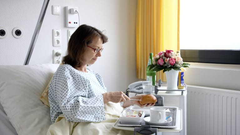 Patientin nimmt im Krankenbett eine Mahlzeit zu sich (Symbolbild): Aus Kostengründen wird bei Asklepios gespart.