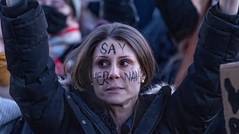 Eine Demonstrantin auf einer Mahnwache für die ermordete Sarah Everard im Märi 2021: "Sagt ihren Namen" steht auf ihrem Gesicht.