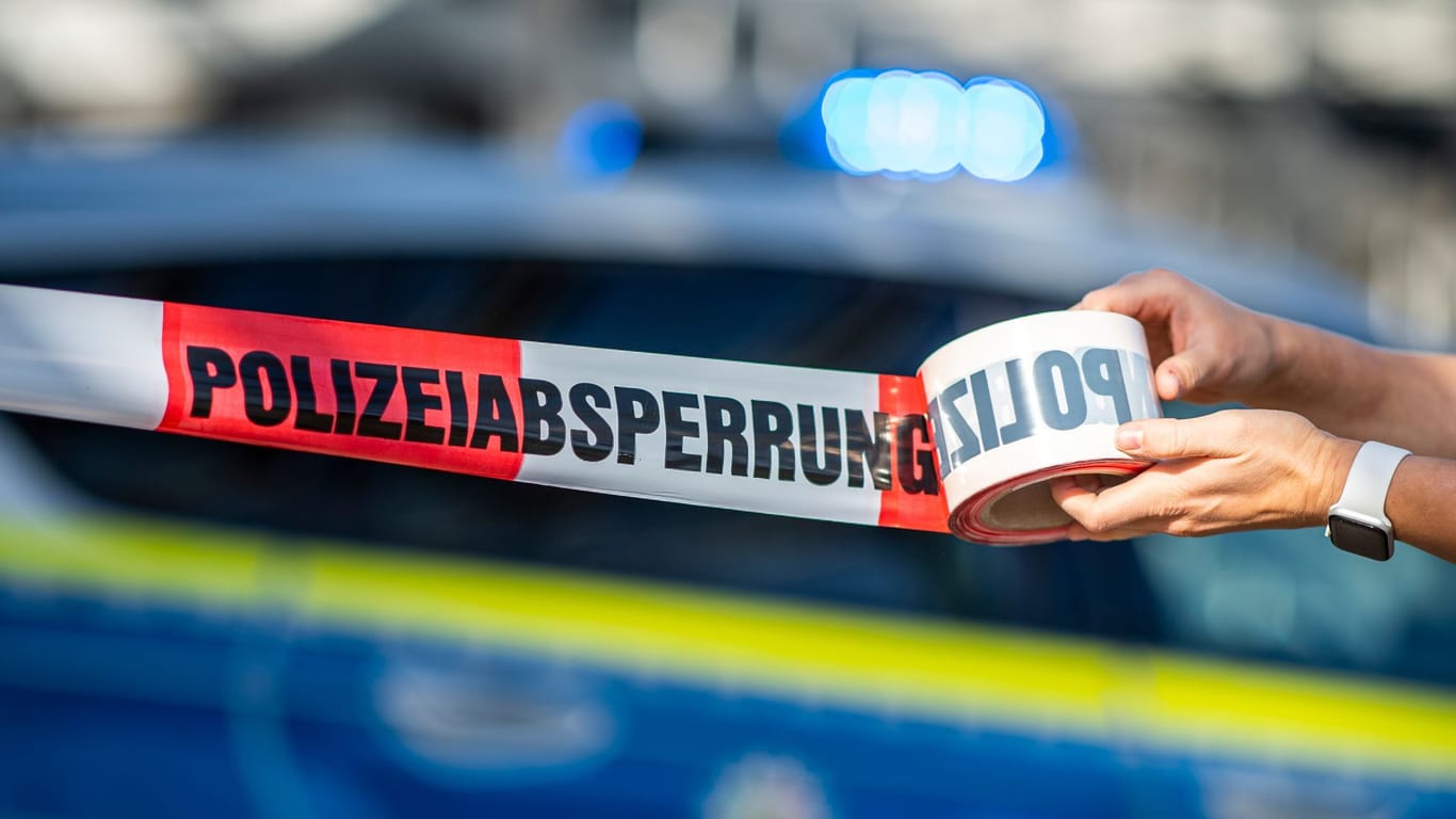 Ein Absperrband wird vor einem Polizeiwagen ausgerollt: In Nützen wurde eine 81-Jährige getötet.