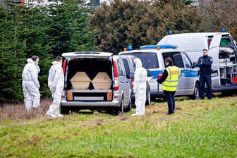 Die Leiche lag in einer Tannenschonung: Mitarbeiter der Spurensicherung der Polizei stehen an einem Leichenwagen.