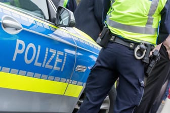 Ein Polizist steht neben seinem Streifenwagen (Symbolbild): Nahe Hannover starb eine Frau wohl nach Gewalteinwirkung.