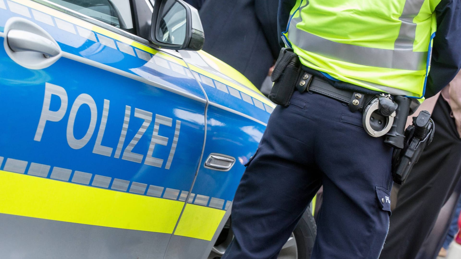 Ein Polizist steht neben seinem Streifenwagen (Symbolbild): Nahe Hannover starb eine Frau wohl nach Gewalteinwirkung.