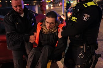 Einsatzkräfte der Berliner Polizei tragen einen Aktivisten der "Letzten Generation" weg: