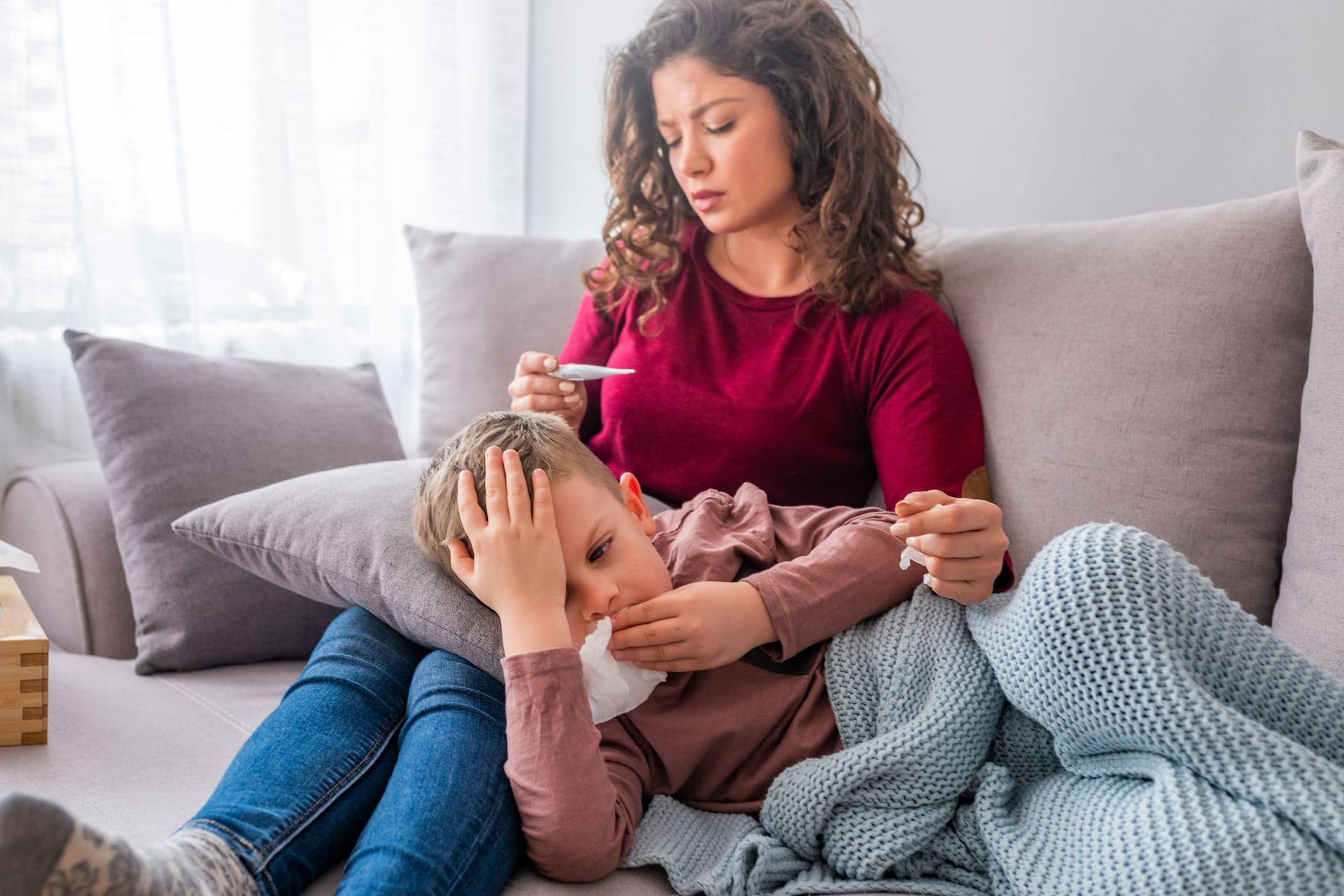 Mutter mit krankem Sohn auf Sofa