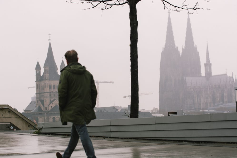 Ein Mann spaziert auf der Deutzer Brücke (Symbolbild): Ob der erwartete Neuschnee in Köln liegen bleibt, ist fraglich.