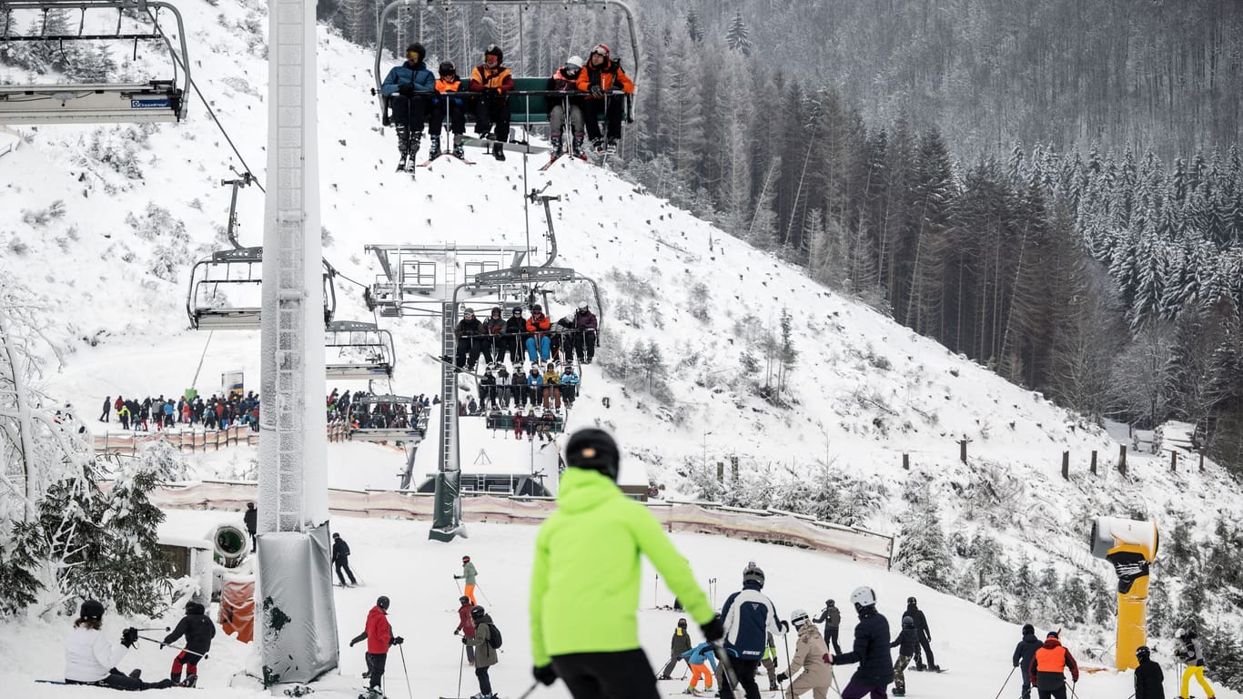 Winterberg: Skifahrer sind bei winterlichem Wetter auf einer Piste unterhalb eines Sesselliftes unterwegs.