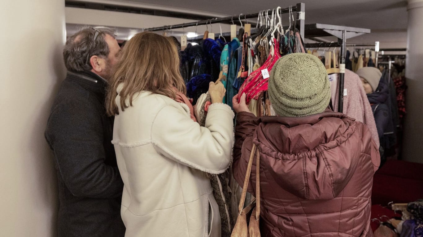 Kostümverkauf: Ein Mann und zwei Frauen schauen sich im Foyer der Semperoper das Angebot an.