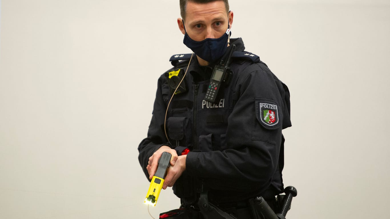 Polizist mit Distanzelektroimpulsgerät (Archivbild): Im aktuellen Fall geht es unter anderem darum, wann genau die Beamten den Taser eingesetzt haben.