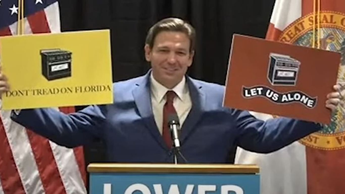 Floridas republikanischer Gouverneur Ron DeSantis hält Plakate mit Gasherden hoch: "Ihr nehmt uns unsere Gasherde nicht weg!"