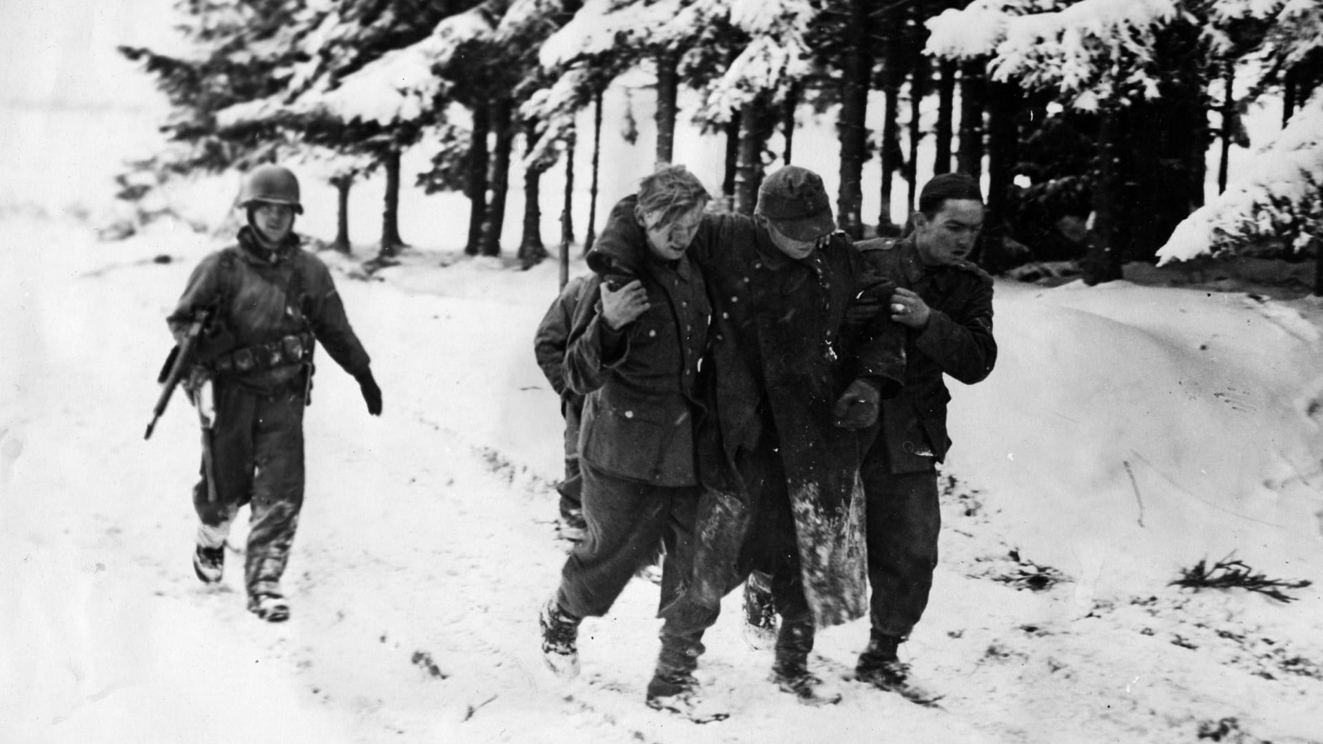 Ein US-Soldat führt im Januar 1945 bei Bastogne gefangene Wehrmachtssoldaten ab.