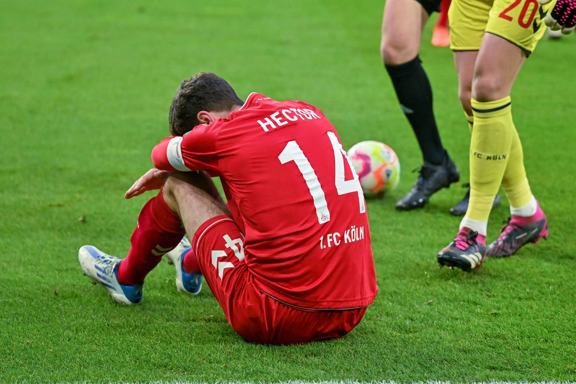 Veltins Arena: Kölns Jonas Hector sitzt nach einem Sturz auf den Kopf auf dem Rasen.