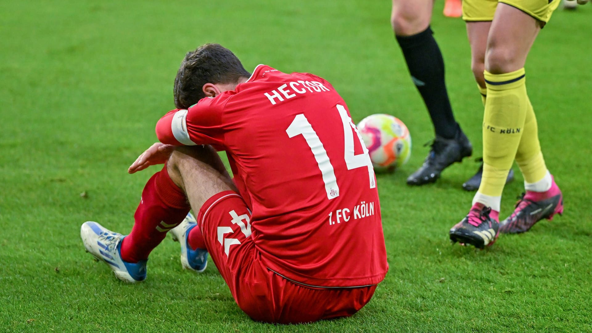 Veltins Arena: Kölns Jonas Hector sitzt nach einem Sturz auf den Kopf auf dem Rasen.