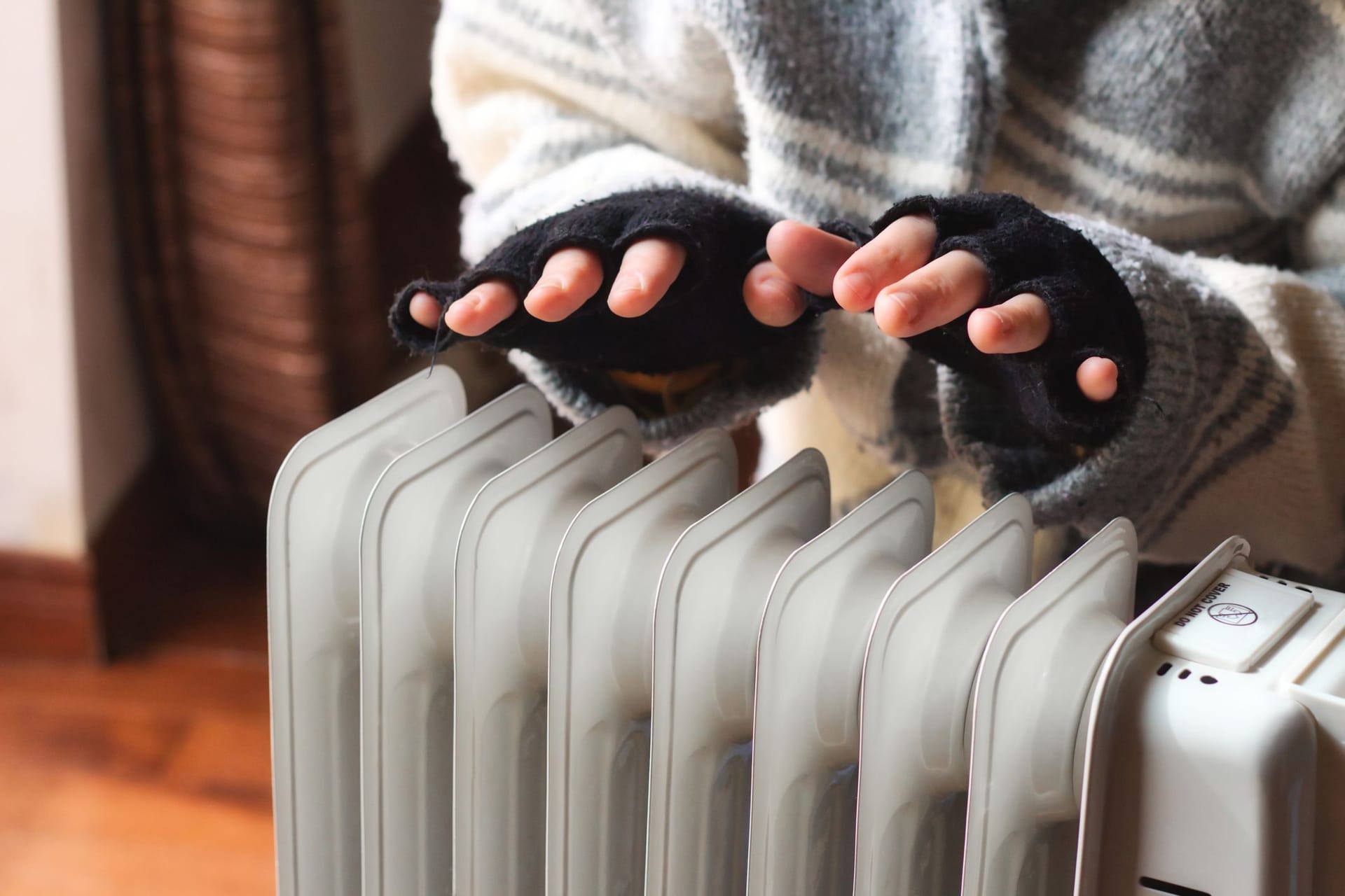 Eine Person wärmt ihre Hände über einer Heizung (Symbolbild): Studierende sollen nicht mehr lange auf ihre Energiepreispauschale warten müssen.