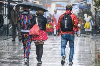 Verkleidete Faschingsfans mit einem Regenschirm (Archivbild): Wie wird das Wetter am Rosenmontag in Hamburg?