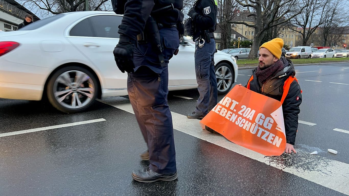 Ein Klima-Demonstrant sitzt auf dem Tempelhofer Damm. Klima-Demonstranten der Klimagruppe Letzte Generation haben in Berlin erneut mit einer Straßenblockade für erhebliche Verkehrsbehinderungen gesorgt.