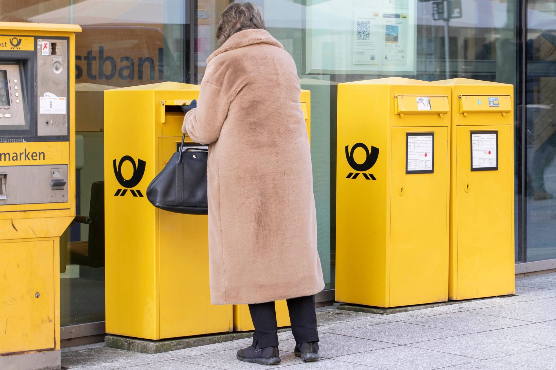 Eine Frau wirft einen Brief ein (Symbolbild): Die Preise für die Briefzustellung könnten sich bald ändern.