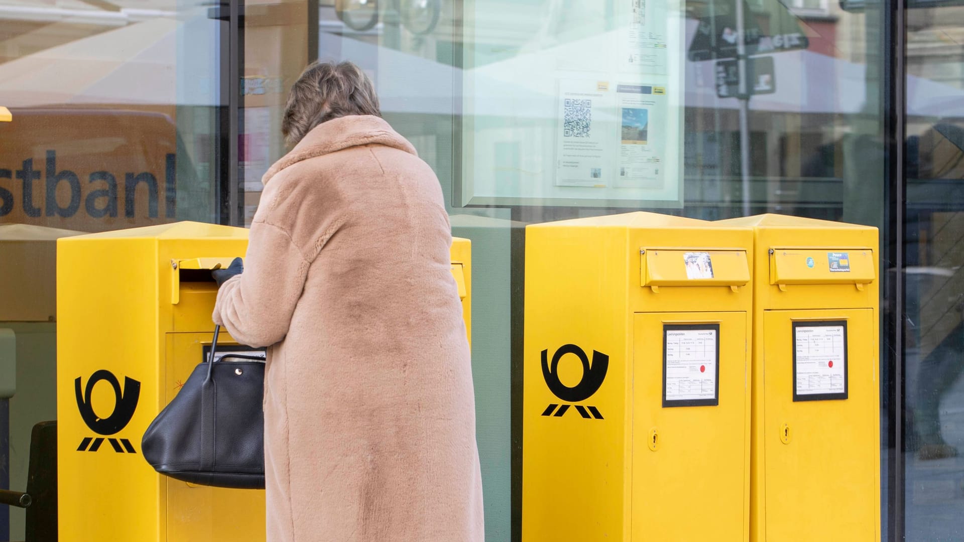 Eine Frau wirft einen Brief ein (Symbolbild): Die Preise für die Briefzustellung könnten sich bald ändern.