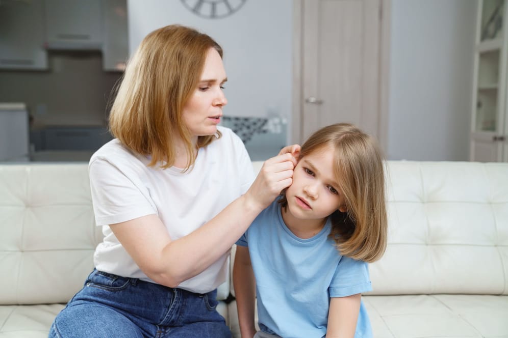 Eine Frau untersucht das Ohr ihres Kindes.