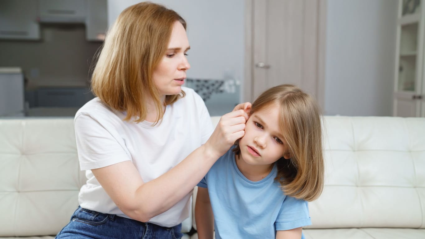 Eine Frau untersucht das Ohr ihres Kindes.