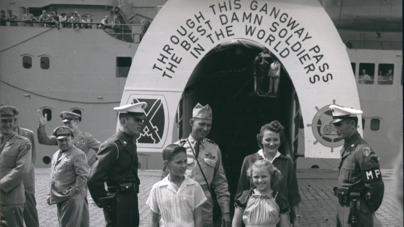 Truppenankunft in Bremerhaven (Archivfoto): Im Jahr 1955 trafen US-Soldaten samt ihren Familien in Bremerhaven ein. Auf einem Banner steht übersetzt: "Diese Gangway passieren die verdammt besten Soldaten der Welt".