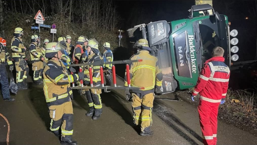 Ein Lastwagen ist gegen einen Baum gerutscht und liegt auf der Seite.