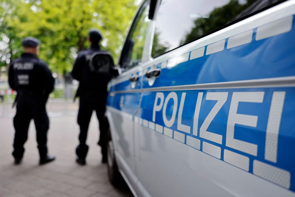 Polizisten stehen neben einem Einsatzfahrzeug (Symbolbild): An einer Ahrensburger Schule wurden Schmierereien mit Gewaltandrohungen entdeckt.