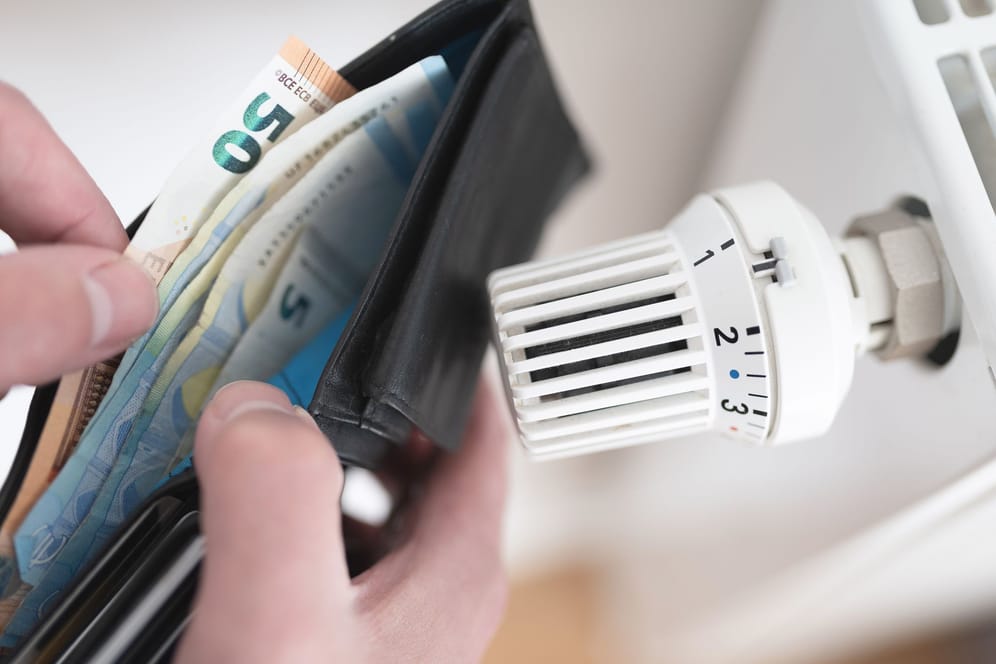 Portemonnaie vor einem Thermostat (Symbolbild): Der Bund zahlt bald die nächste Energiepreispauschale aus.