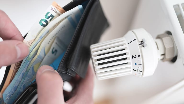 Portemonnaie vor einem Thermostat (Symbolbild): Der Bund zahlt bald die nächste Energiepreispauschale aus.