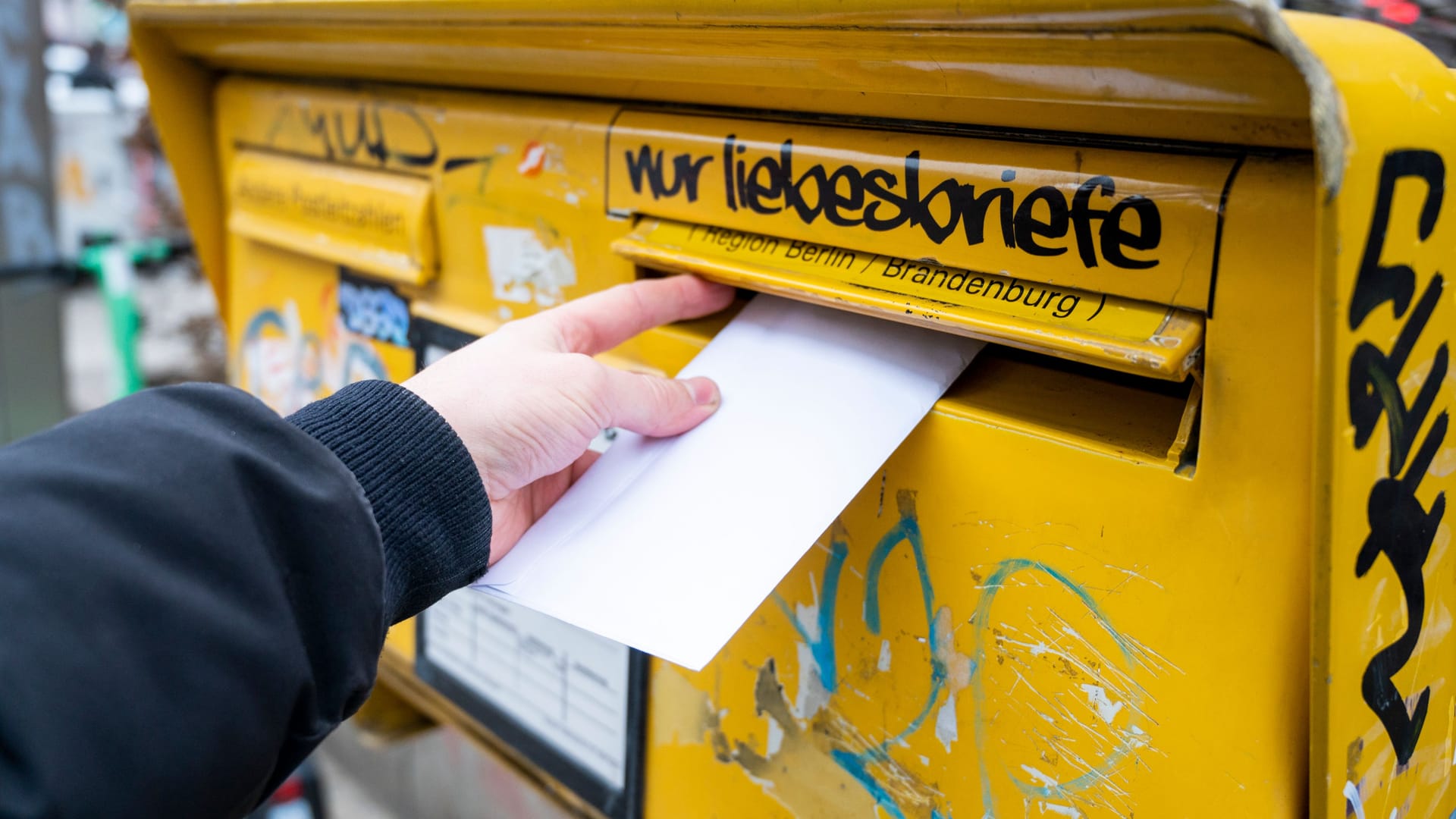 Ein Mann wirft einen Brief in einen Briefkasten (Symbolbild): Ein unbefristeter Arbeitskampf bei der Deutschen Post dürfte erhebliche Folgen für den Versand haben.