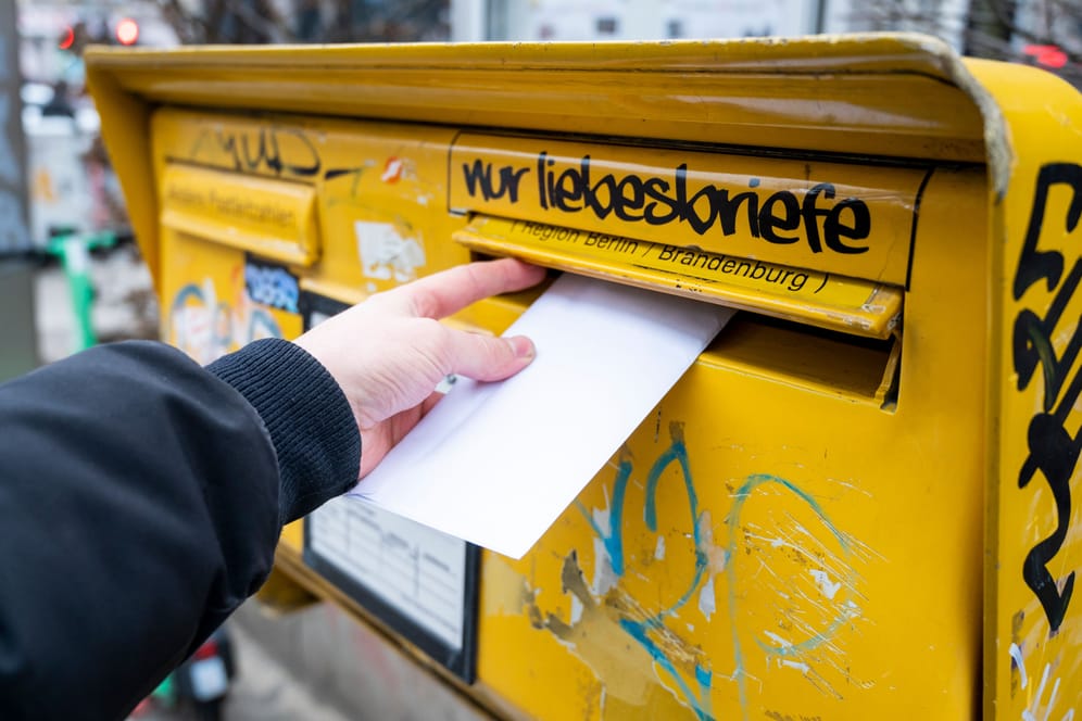 Ein Mann wirft einen Brief in einen Briefkasten (Symbolbild): Ein unbefristeter Arbeitskampf bei der Deutschen Post dürfte erhebliche Folgen für den Versand haben.