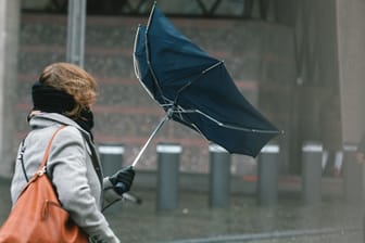 Eine Frau mit ihrem Regenschirm (Archivbild): Im Rheinland wird es zu Weihnachten regnericsh und stürmisch.