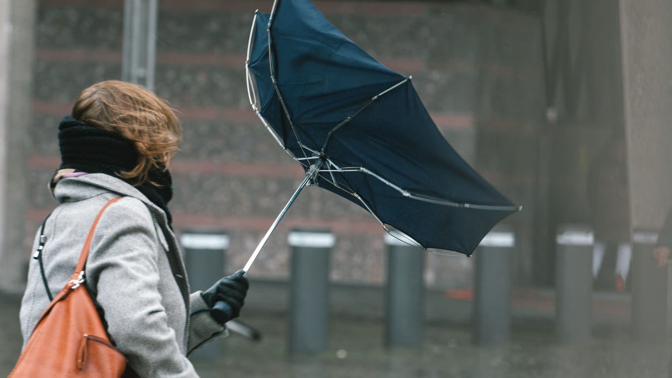 Eine Frau mit ihrem Regenschirm (Archivbild): Im Rheinland wird es zu Weihnachten regnericsh und stürmisch.
