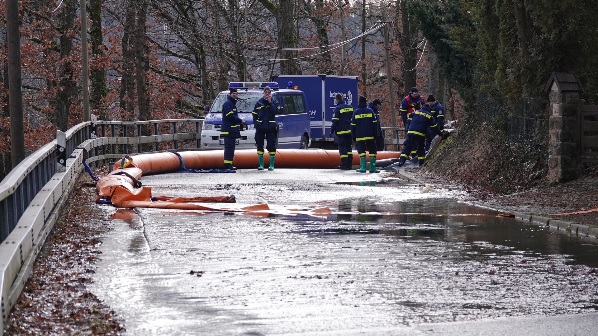 Straße am Stausee bei Dippoldiswalde: Das THW versucht mit orangenen Sperren das auslaufende Abwasser zu stauen, um es später abzupumpen.