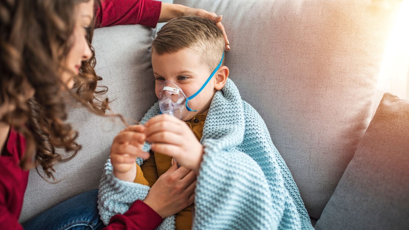 Eine Mutter hilft ihrem Kind beim Inhalieren. Mukoviszidose ist eine seltene Erkrankung, die oft schon im frühen Kindesalter auftritt.