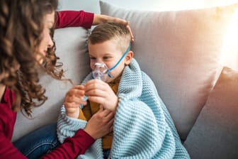 Eine Mutter hilft ihrem Kind beim Inhalieren. Mukoviszidose ist eine seltene Erkrankung, die oft schon im frühen Kindesalter auftritt.