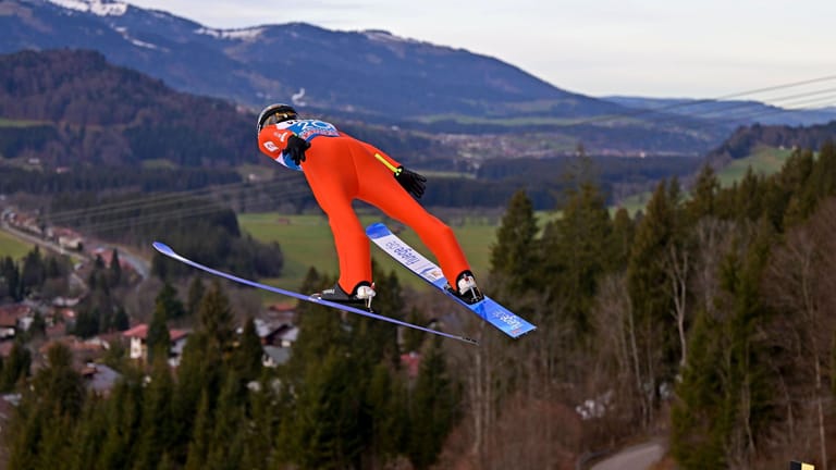 Ein Skispringer in der Luft: Immer häufiger blicken die Athleten bei ihren Flügen ins Grüne statt in eine Winterlandschaft.