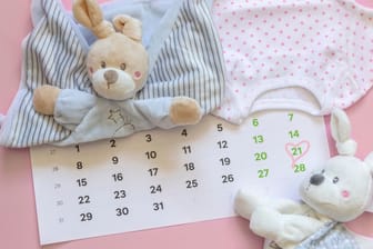 Ein Kalenderblatt mit markiertem Datum, umgeben von Babyspielzeug