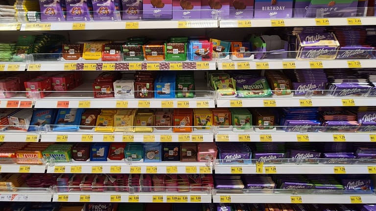 Supermarktregal mit Süßigkeiten bei Edeka (Symbolbild): Für gewisse Markenartikel bezahlen Kunden in Deutschland deutlich mehr als in Supermärkten der Nachbarländer Frankreich oder Holland.