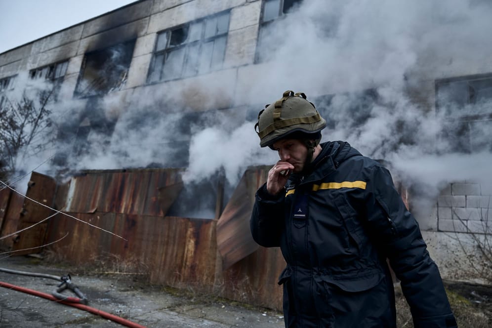 Ein Feuerwehrmann raucht vor einem brennenden Gebäude in Cherson (Archivbild): Auch am Dienstag gab es wieder Angriffe auf die Stadt.