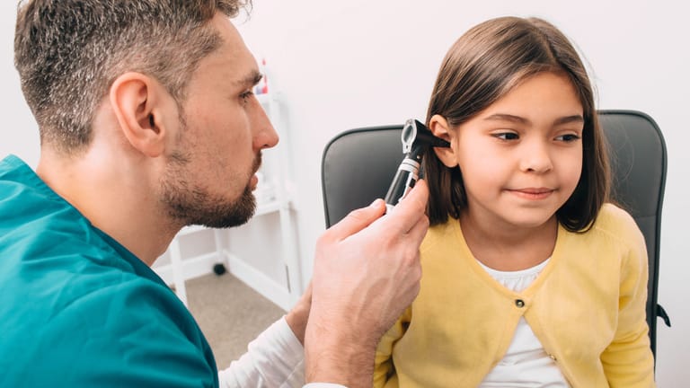 Arzt untersucht das Ohr eines Mädchens