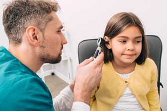 Arzt untersucht das Ohr eines Mädchens