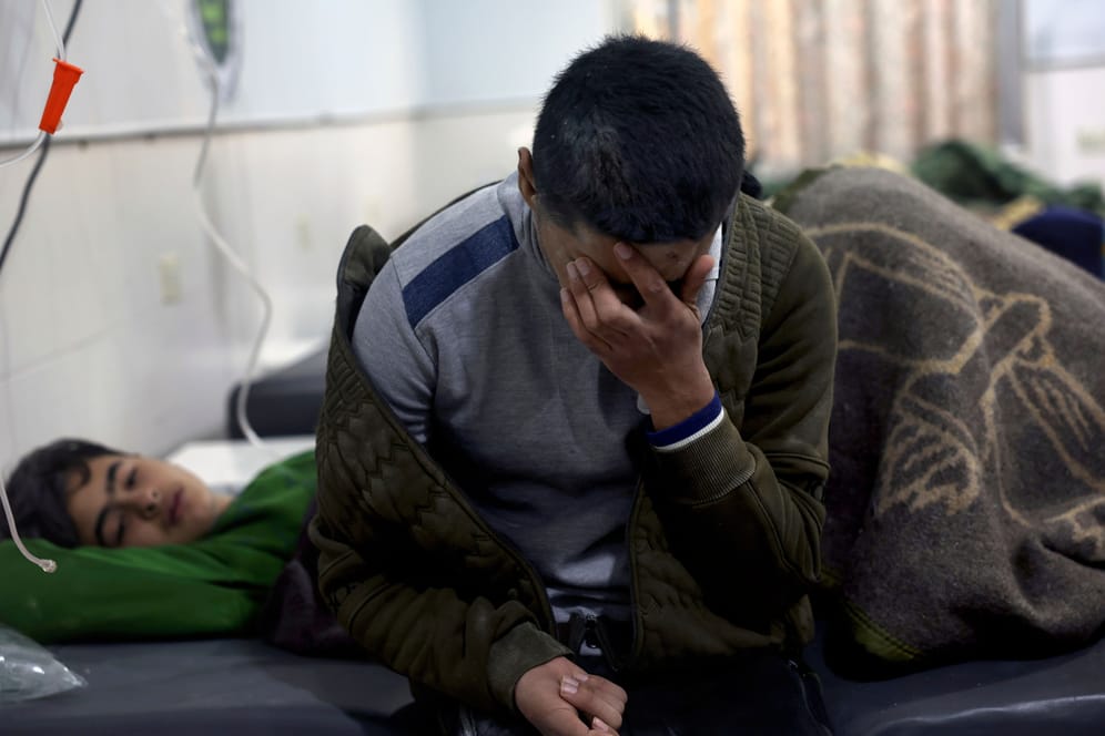 Ein Mann hält sich die Hand vors Gesicht, während Erdbebenopfer in einem Krankenhaus im syrischen Darkush behandelt werden.